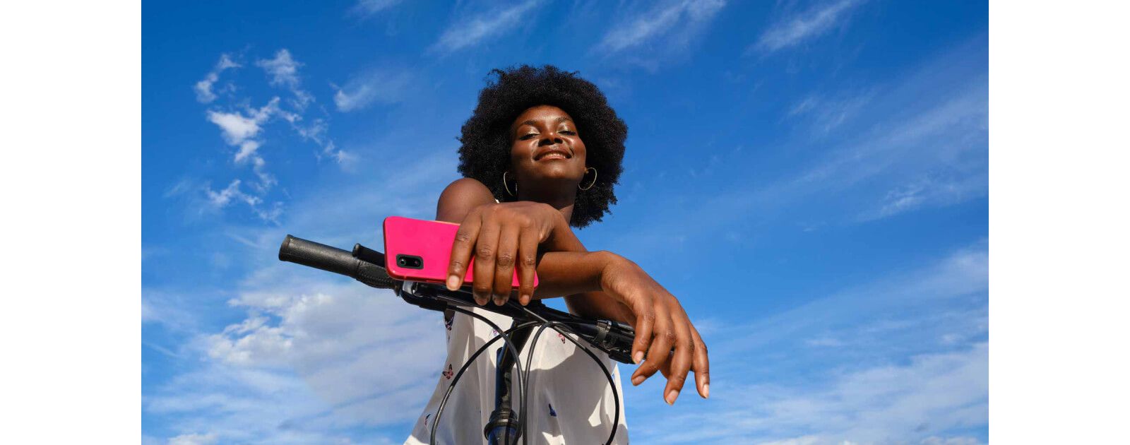 Woman leaning on a bike handlebar holding a magenta T-Mobile phone